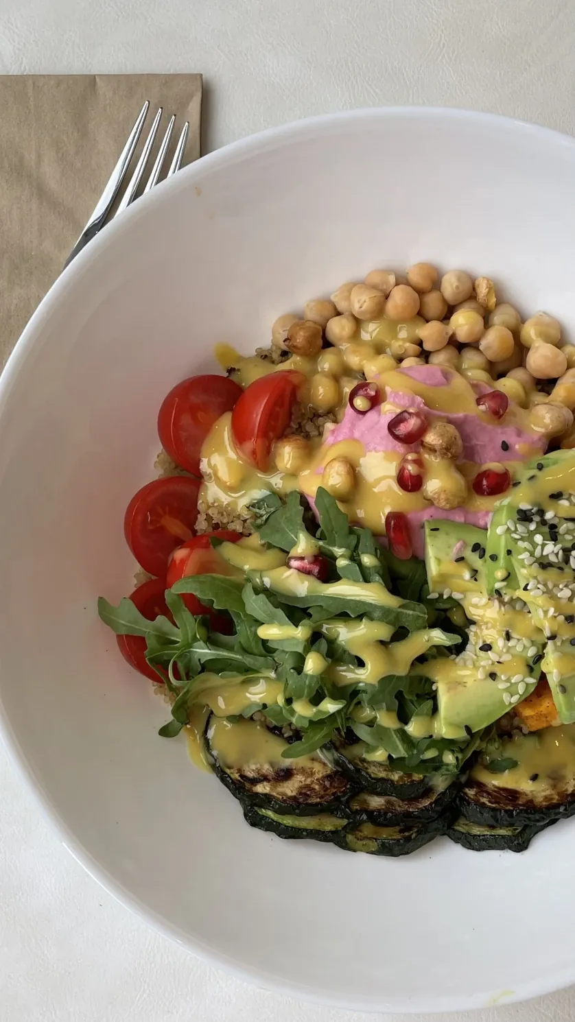 Bowl mit gerösteten Kichererbsen, Rote-Bete-Creme, Avocado, Rucola, Granatapfel und gegrillter Zucchini